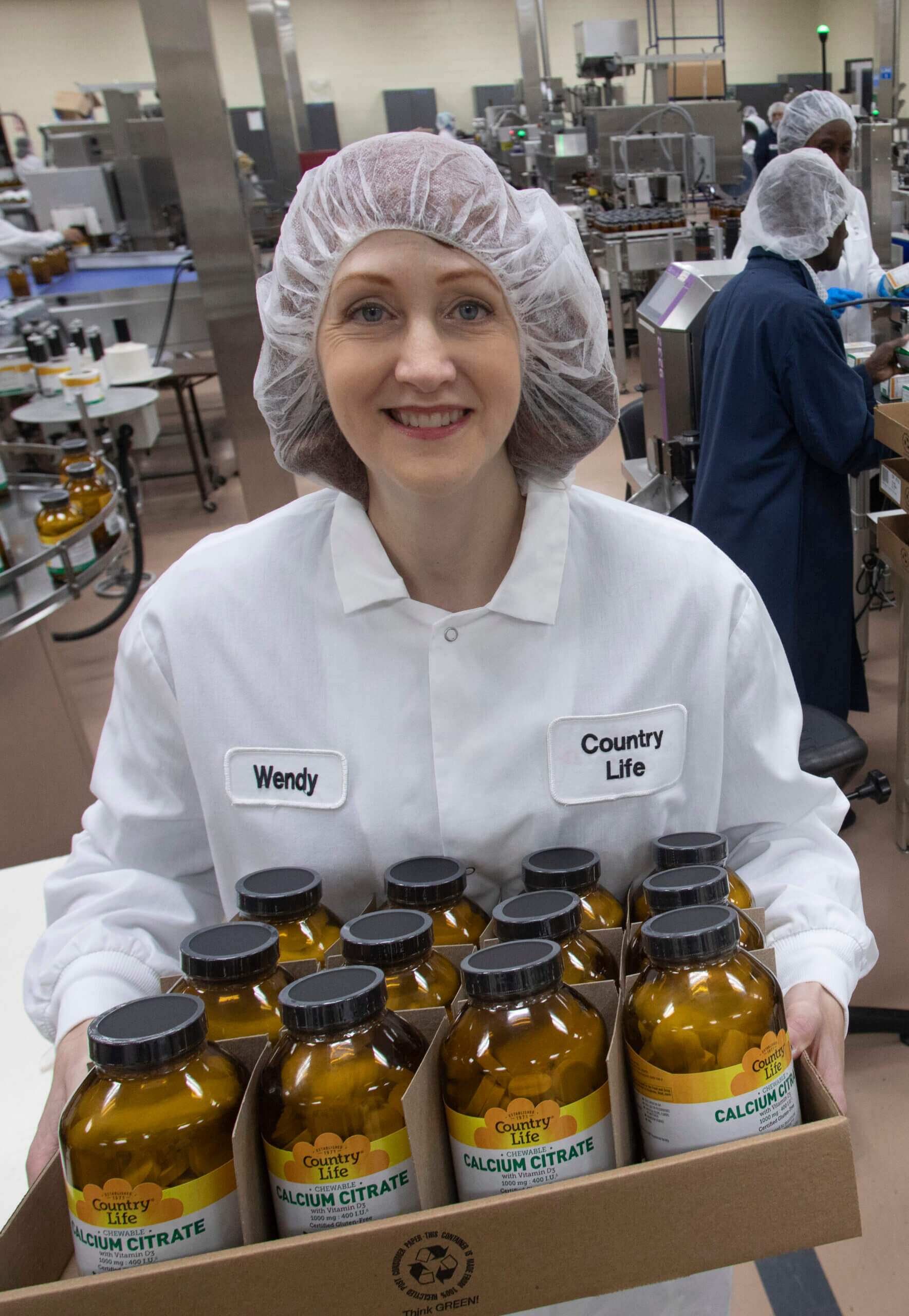 Woman holding tray of supplement bottles.